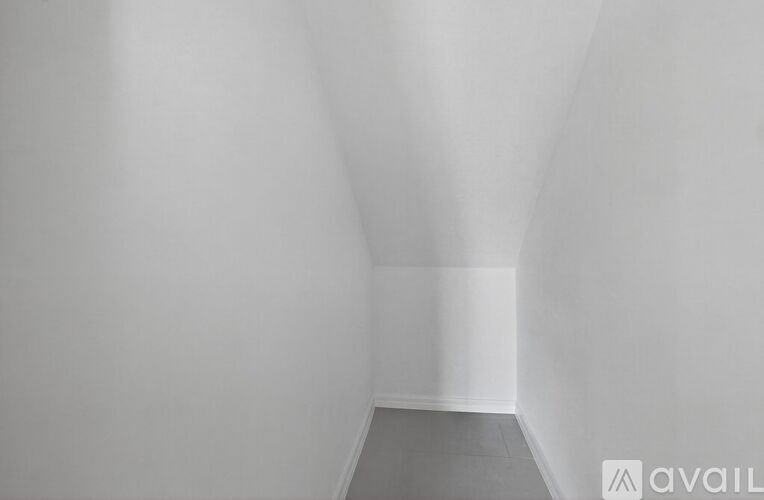 A white room with a grey floor and a white wall.