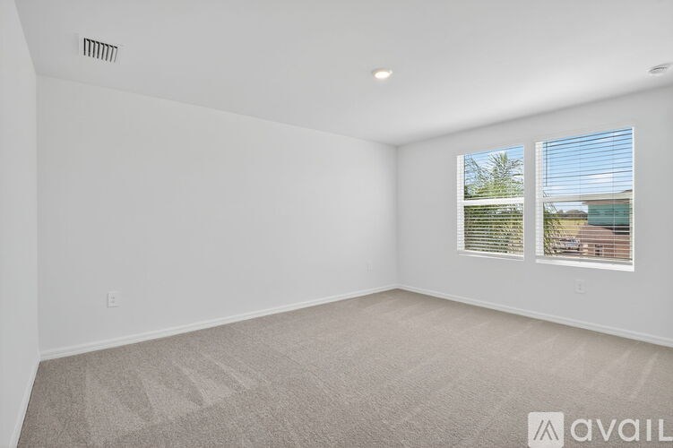A room with a carpeted floor and a window showing a view of a house.