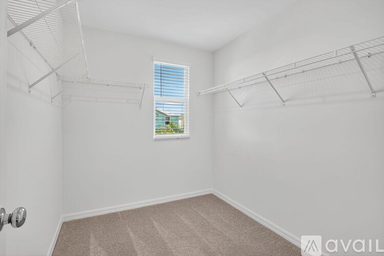 A room with white walls and a window with blinds.