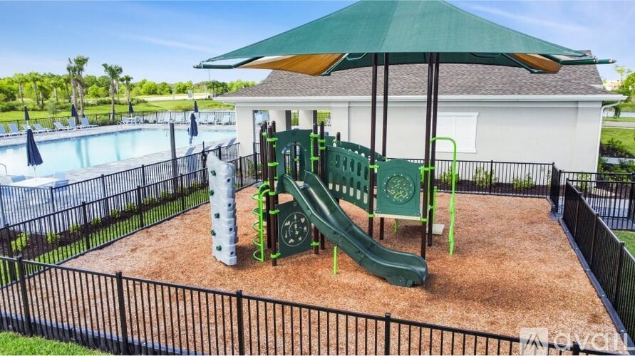 A playground with a green slide and a white building in the background.
