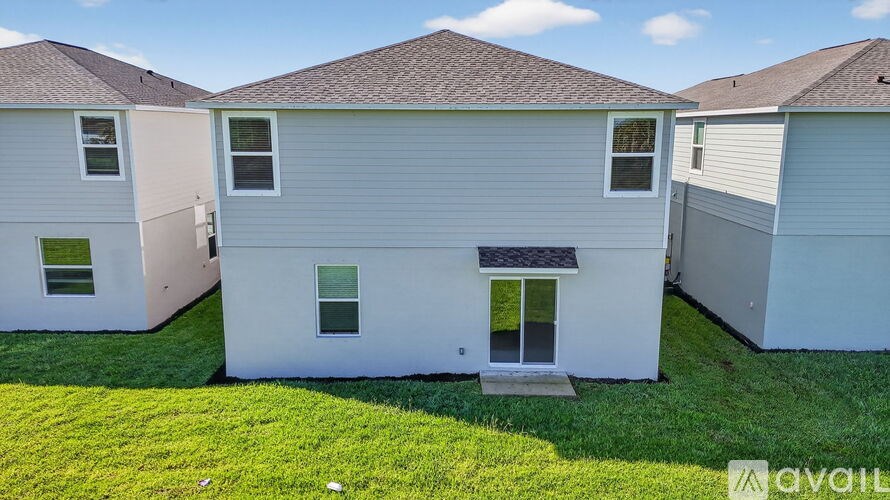 A white house with a brown roof is surrounded by a green lawn.