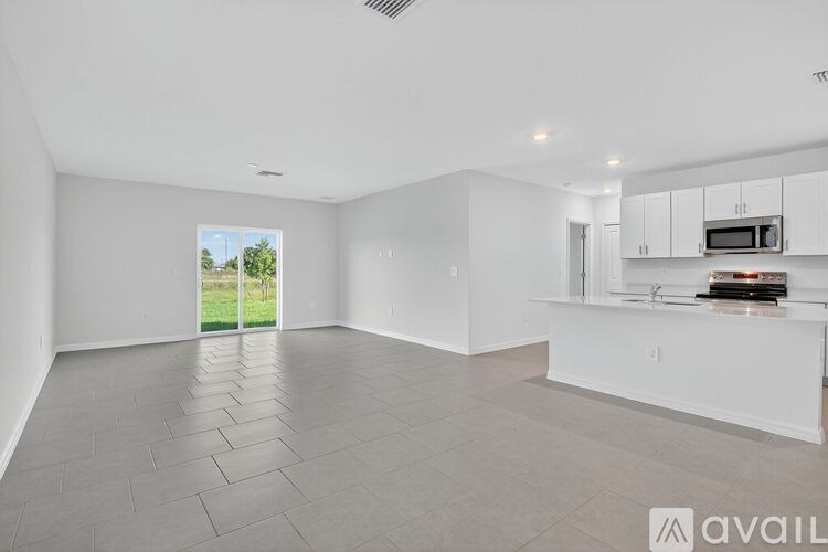 A spacious, empty room with a sliding glass door leading to a green outdoor area.