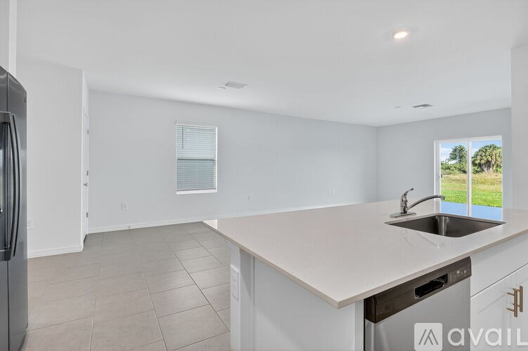 A kitchen with white cabinets and a large island with a sink.