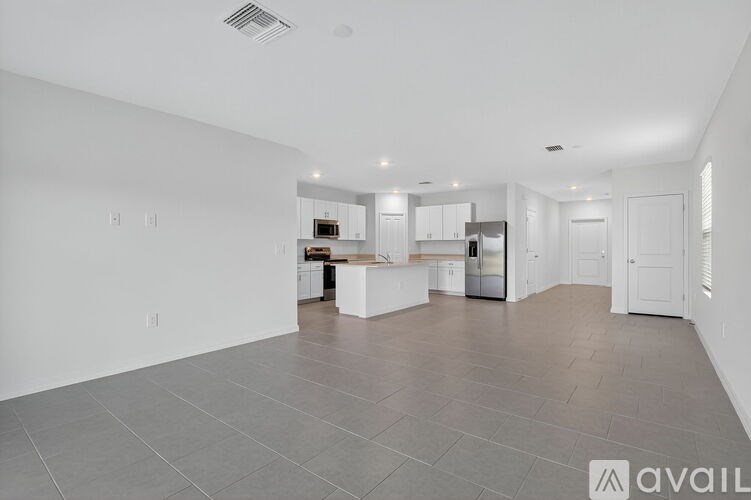 A spacious kitchen and living room with white cabinets and a central island.