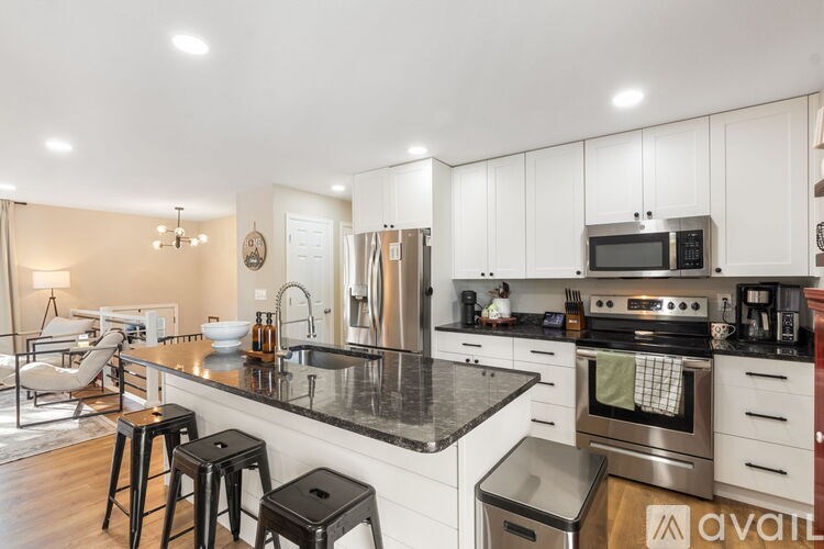 A modern kitchen with white cabinets and a black countertop.
