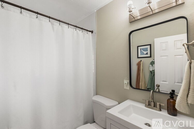 A white bathroom with a toilet, sink, and shower.