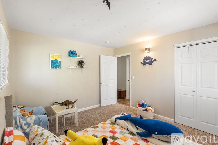 A room with a bed, a chair, and a toy dog on the floor.