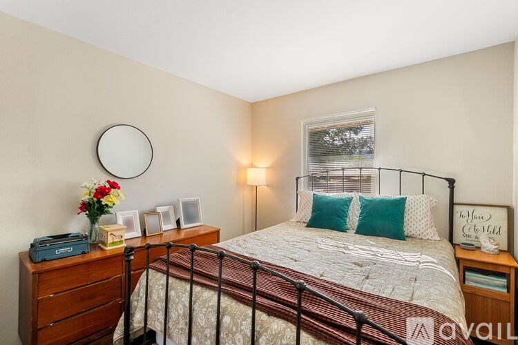 A bedroom with a bed, nightstand, and a round mirror on the wall.
