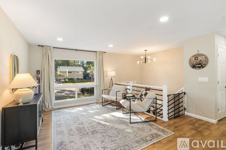 A living room with a sofa, a chair, a lamp, and a large window with a view of the street.