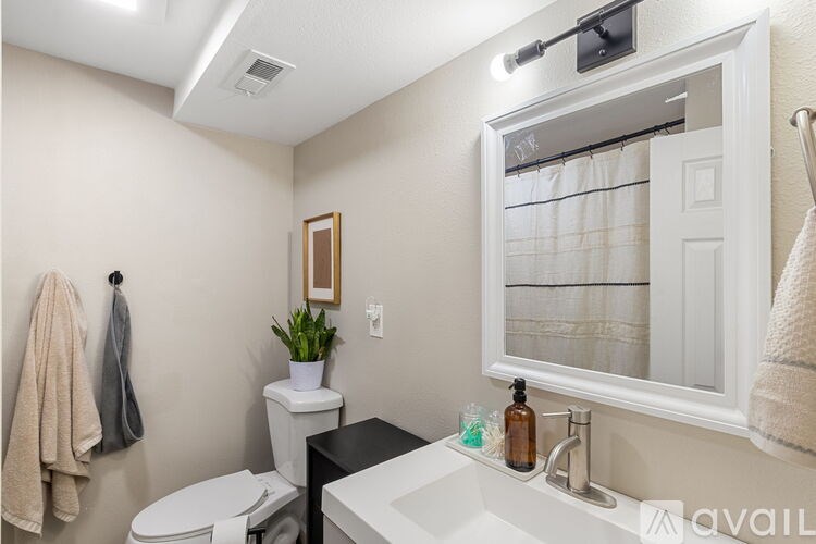 A bathroom with a toilet, sink, and mirror.