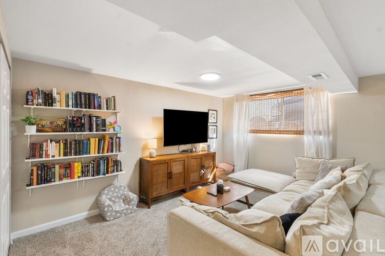 A living room with a white couch, a television, and a bookshelf filled with books.