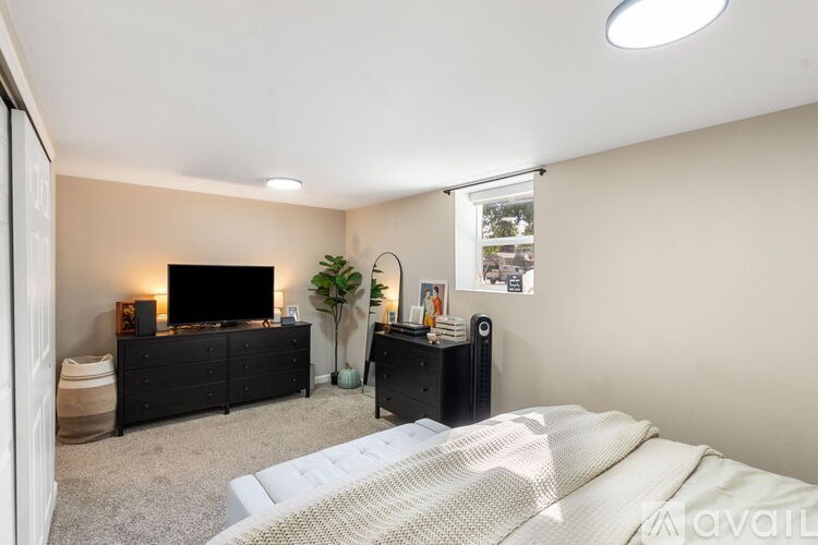 A bedroom with a bed, dresser, and a television.