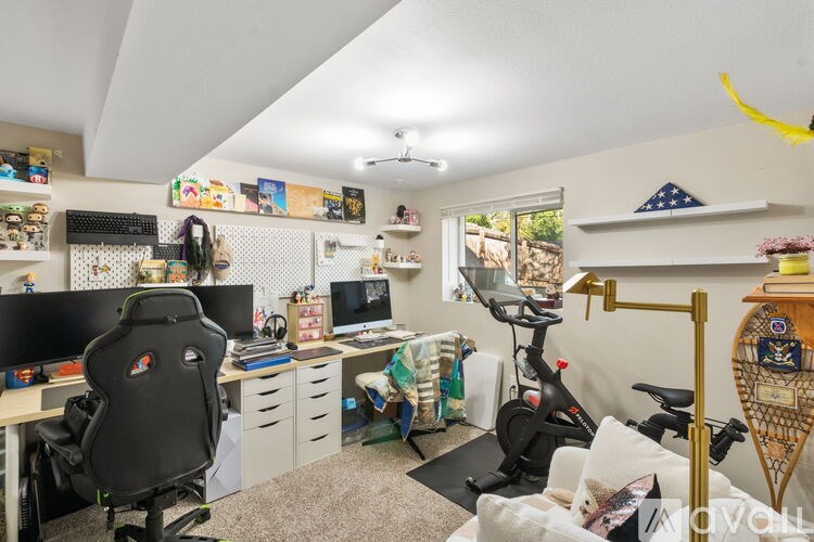 A room with a desk, chair, and exercise bike.