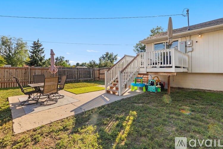 A backyard with a patio, lawn, and a deck.