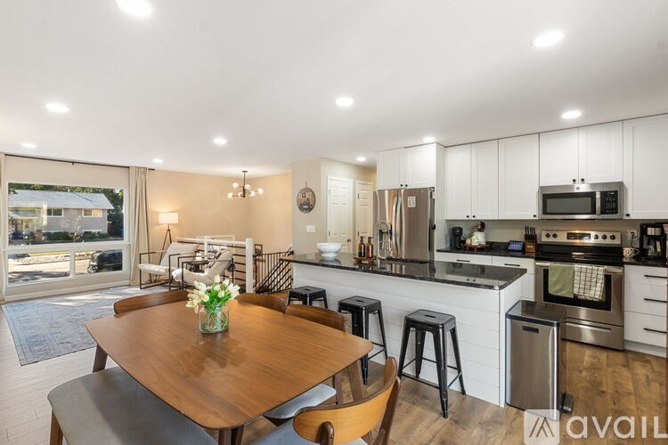 A modern kitchen with a wooden table and bar stools.