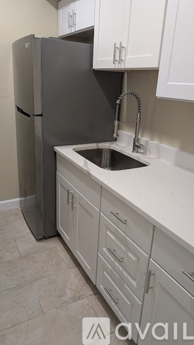A kitchen with a black refrigerator and white cabinets.