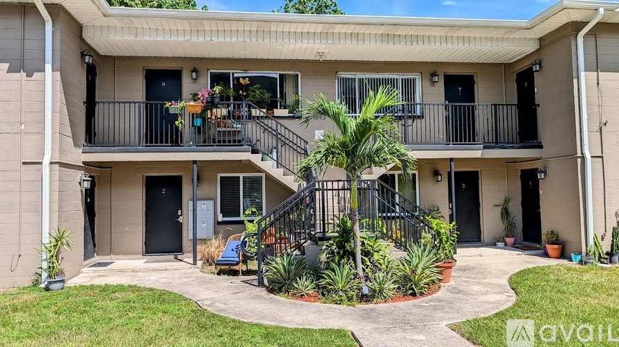 A balcony with a black railing and a palm tree in front of a building.