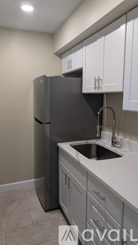 A kitchen with a grey fridge and white cabinets.