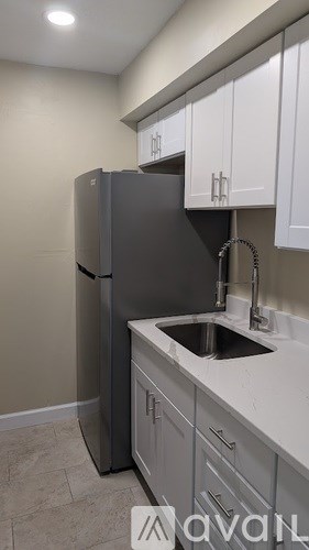 A kitchen with a grey fridge and white cabinets.