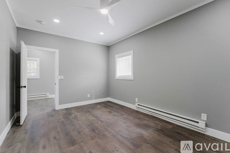 A room with wooden flooring and a door leading to another room.