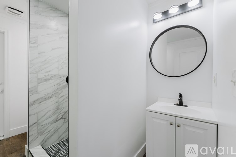A bathroom with a marble wall and a round mirror.
