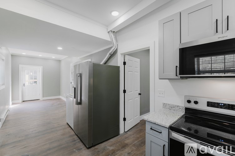A kitchen with a stainless steel refrigerator and oven, and white cabinets.