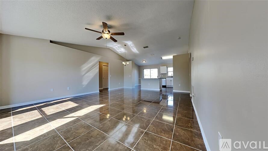 A spacious room with a ceiling fan and tiled flooring.