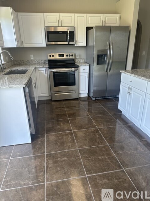 A kitchen with white cabinets and a tile floor.