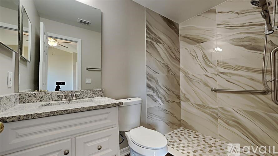 A bathroom with a marble counter top and a white toilet.