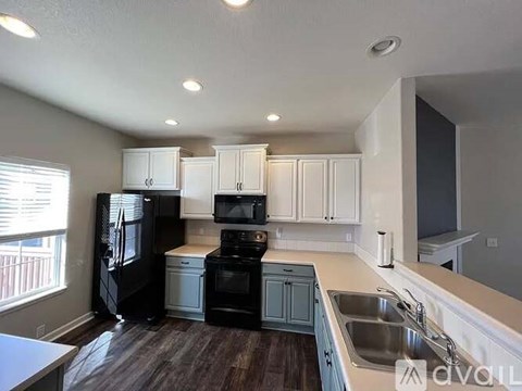 A kitchen with black appliances and white cabinets.
