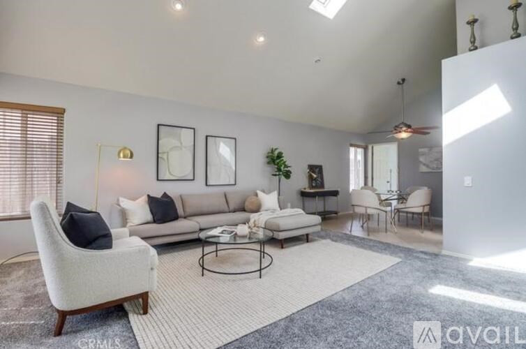 A living room with a white sofa, a grey armchair, a coffee table, and a rug.