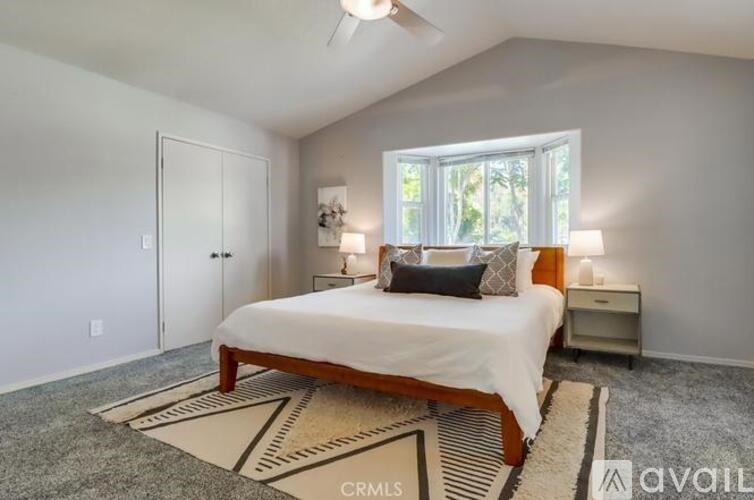 A bedroom with a bed, nightstand, and window.