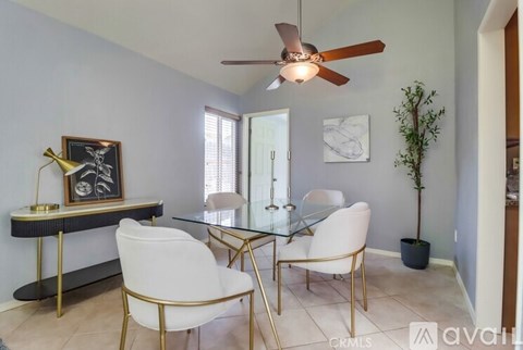 A living room with a glass table and white chairs.