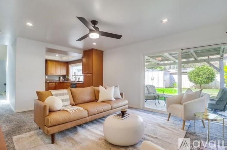 A living room with a brown sofa and a white ottoman.