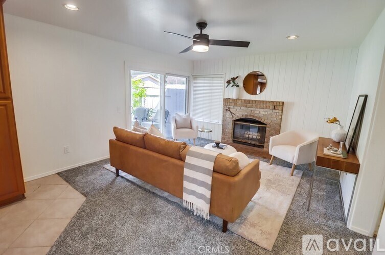 A living room with a brown couch and a fireplace.