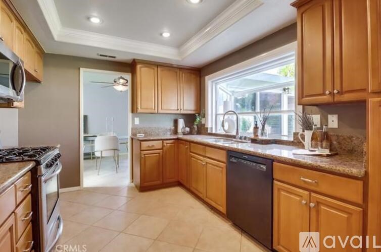 A kitchen with wooden cabinets and a black dishwasher.