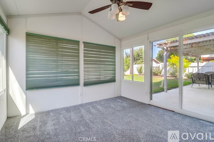 A sunny day in a room with a ceiling fan and sliding glass doors.