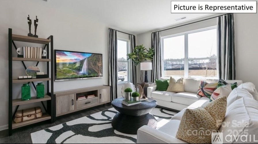 A living room with a white couch, a coffee table, and a television.