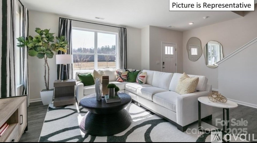 A living room with a white couch, a black coffee table, and a large window.
