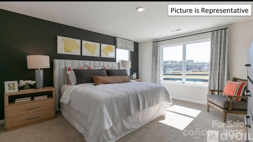 A bedroom with a large bed, a nightstand with a lamp, and a window with a view of the water.
