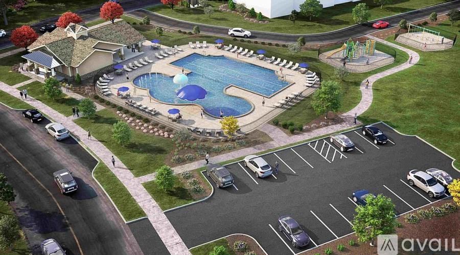 A large outdoor pool surrounded by a grassy area and a parking lot.