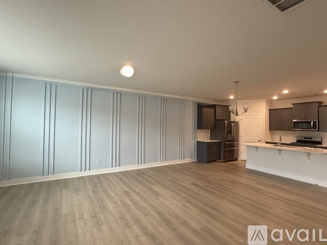 A spacious kitchen and living room with wooden flooring and white walls.