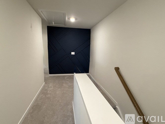 A hallway with a white bench and a black door.