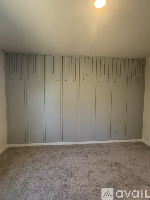 A room with a carpeted floor and a wall with a row of panels.