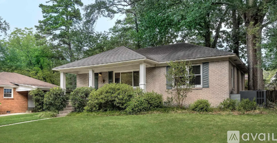 A house with a front yard and a tree in the background.