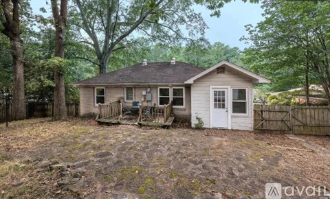 A small house with a white door is surrounded by trees.