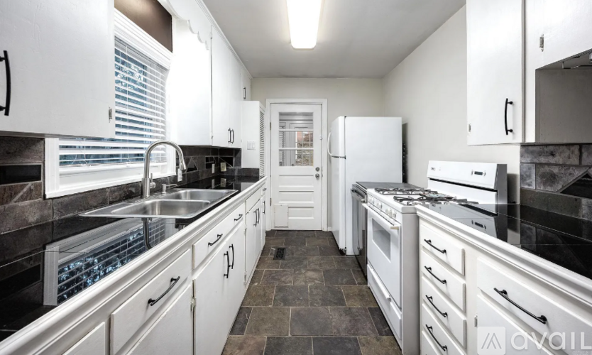 A modern kitchen with white cabinets and black countertops.