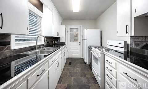 A modern kitchen with white cabinets and black countertops.