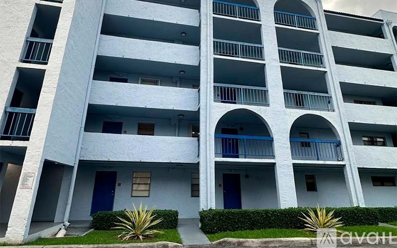 A tall white building with balconies and doors.