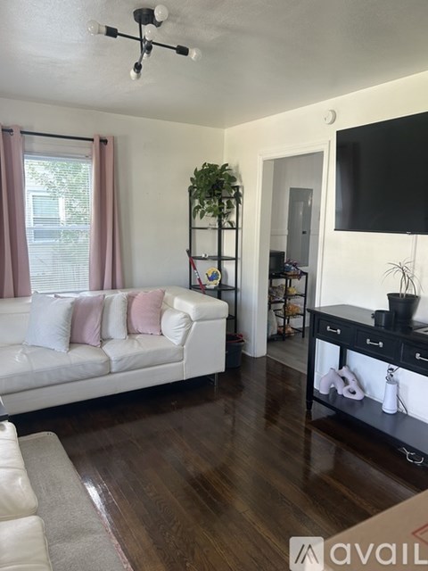 A living room with a white couch and a wooden floor.